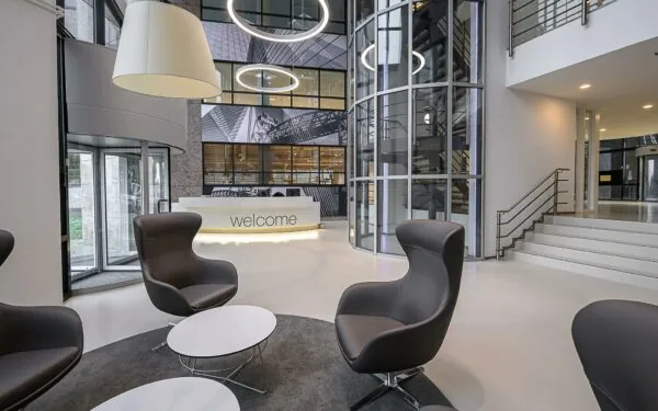 Moderne ontvangsthal van het Rivium Quadrant met loungezitjes, een receptiebalie en glazen lift.
